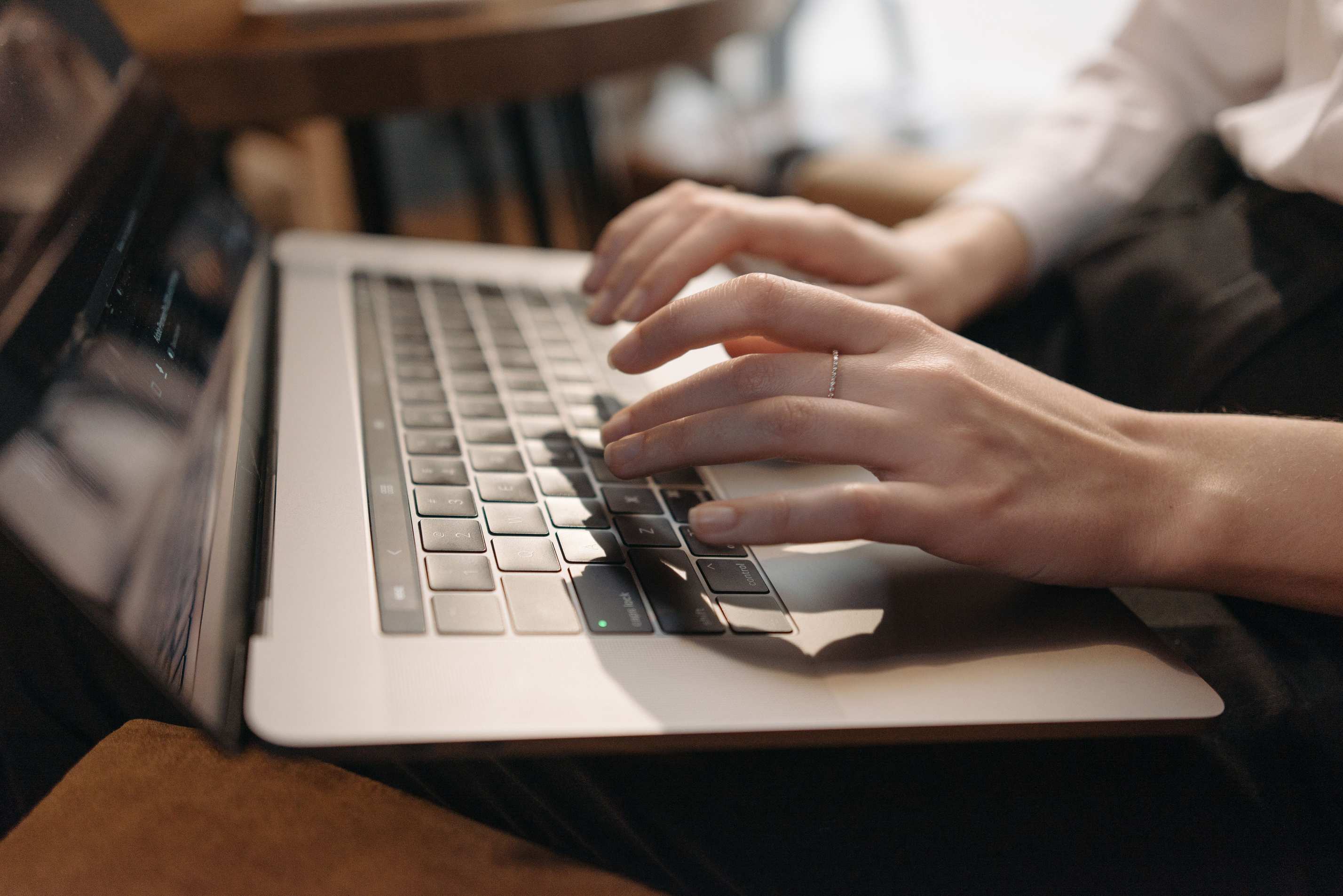 Close-up of hands typing on a laptop keyboard